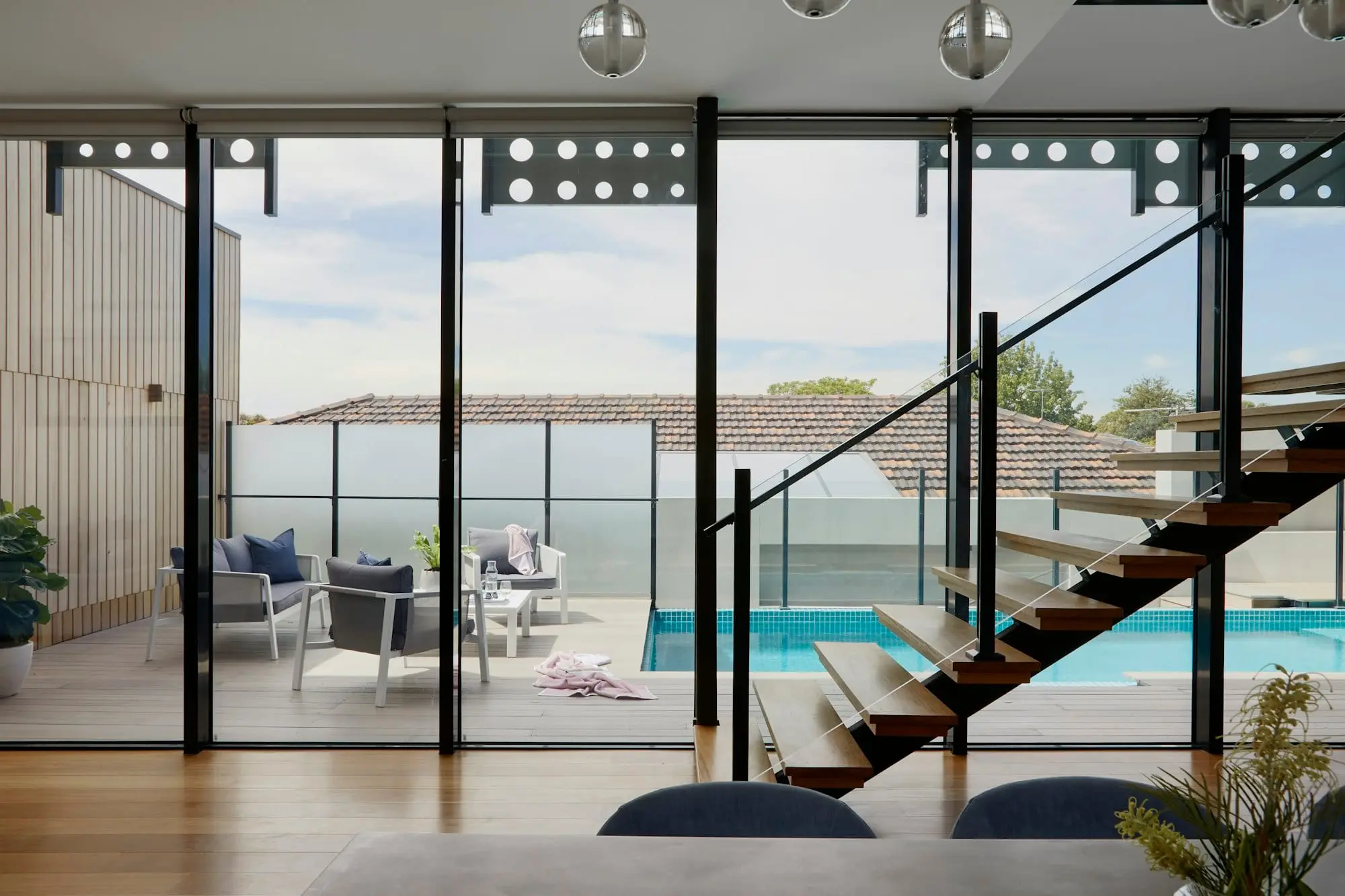 Escada com degraus em madeira e caixilhos metálicos voltados para a piscina