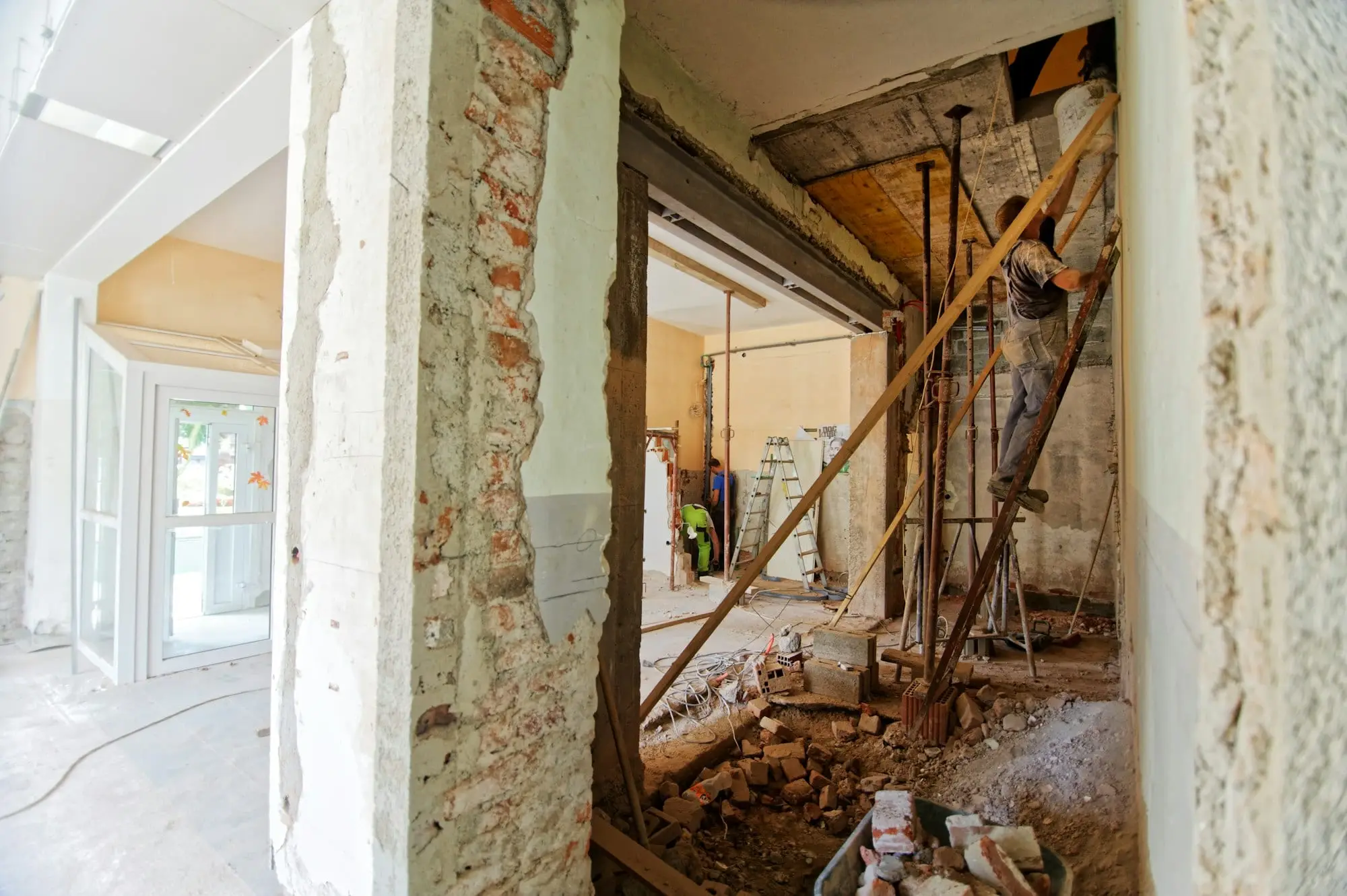 Ambiente em obra com paredes descascadas, alvenaria aparente e escoramento de madeira